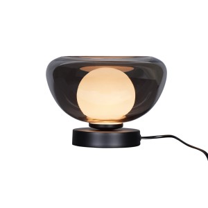 Lampada da tavolo con paralume in vetro grigio e base nera.