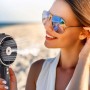 Donna che usa il ventilatore t.b.t. sulla spiaggia per una brezza fresca.