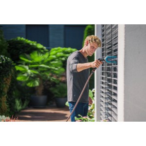 Uomo pulisce le persiane con la spazzola per persiane Gardena Cleansystem con raccordo per l'acqua.