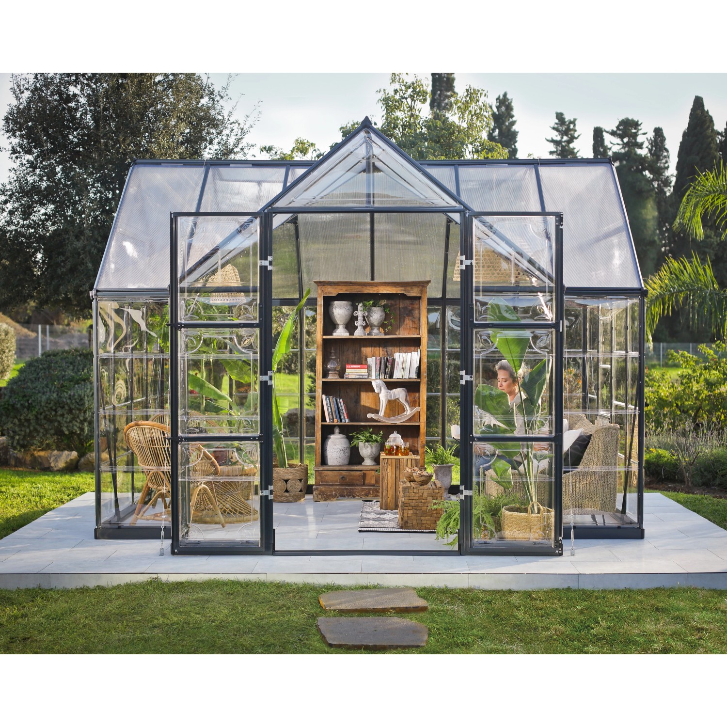 Serra Palram Canopia Victory Orangerie con libreria e piante in giardino.