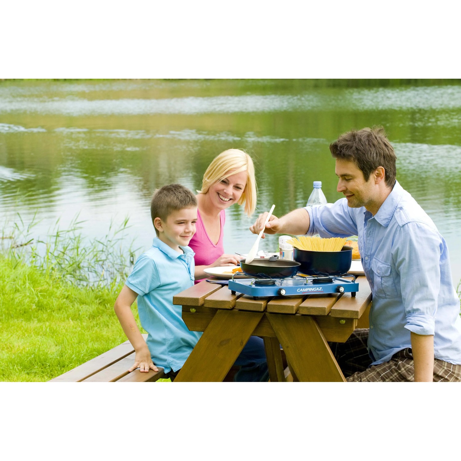 Famiglia in campeggio con fornello da campeggio t.b.t. vicino al lago.