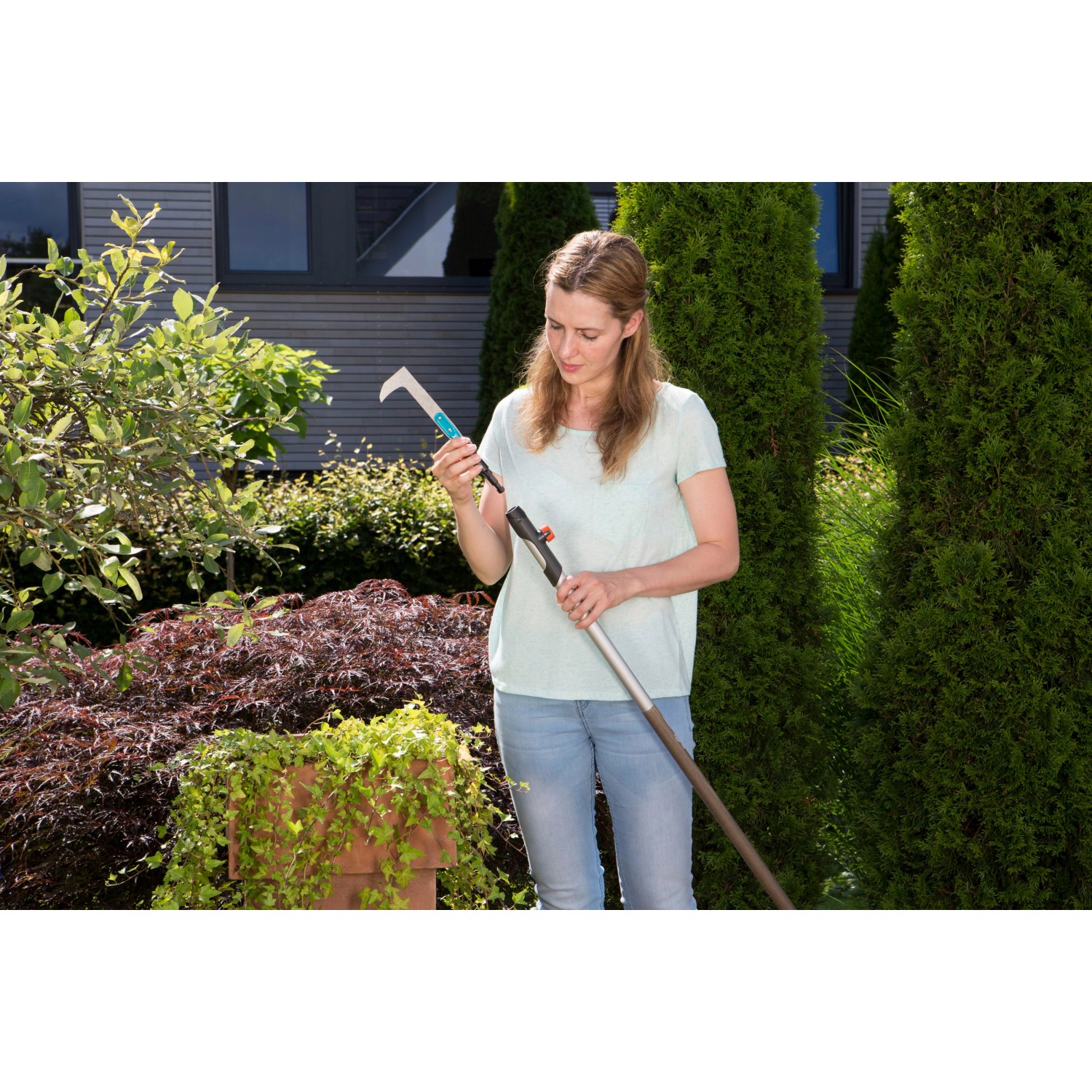 Donna che assembla il raschietto per giunti Gardena combisystem con manico in giardino.