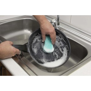Pulizia di una padella con spugna nel lavandino. Categoria: Attrezzi per la pulizia.