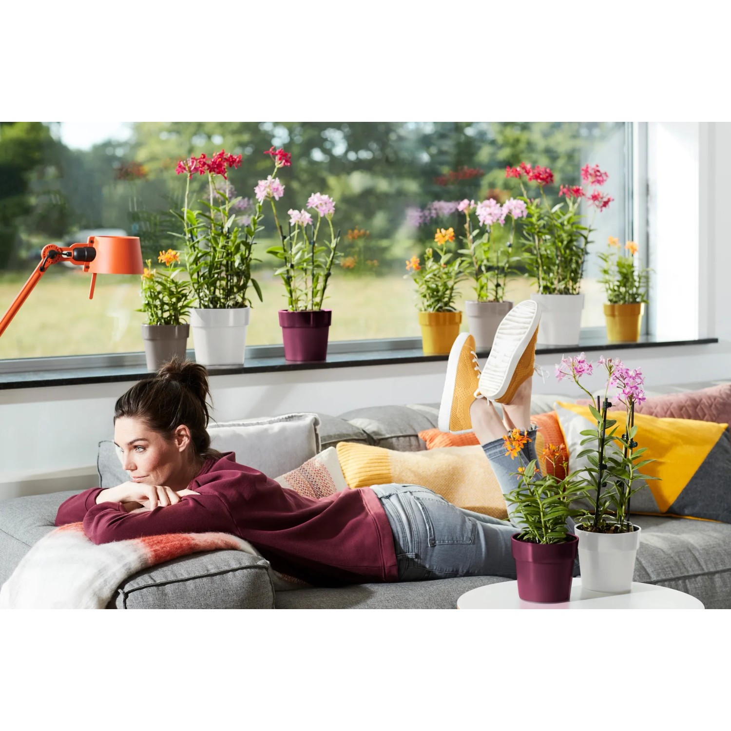 Donna rilassata sul divano con vasi Elho B.for Original in vari colori.