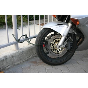 Motocicletta assicurata con lucchetto a cavo t.b.t. sulla ruota anteriore e recinzione.