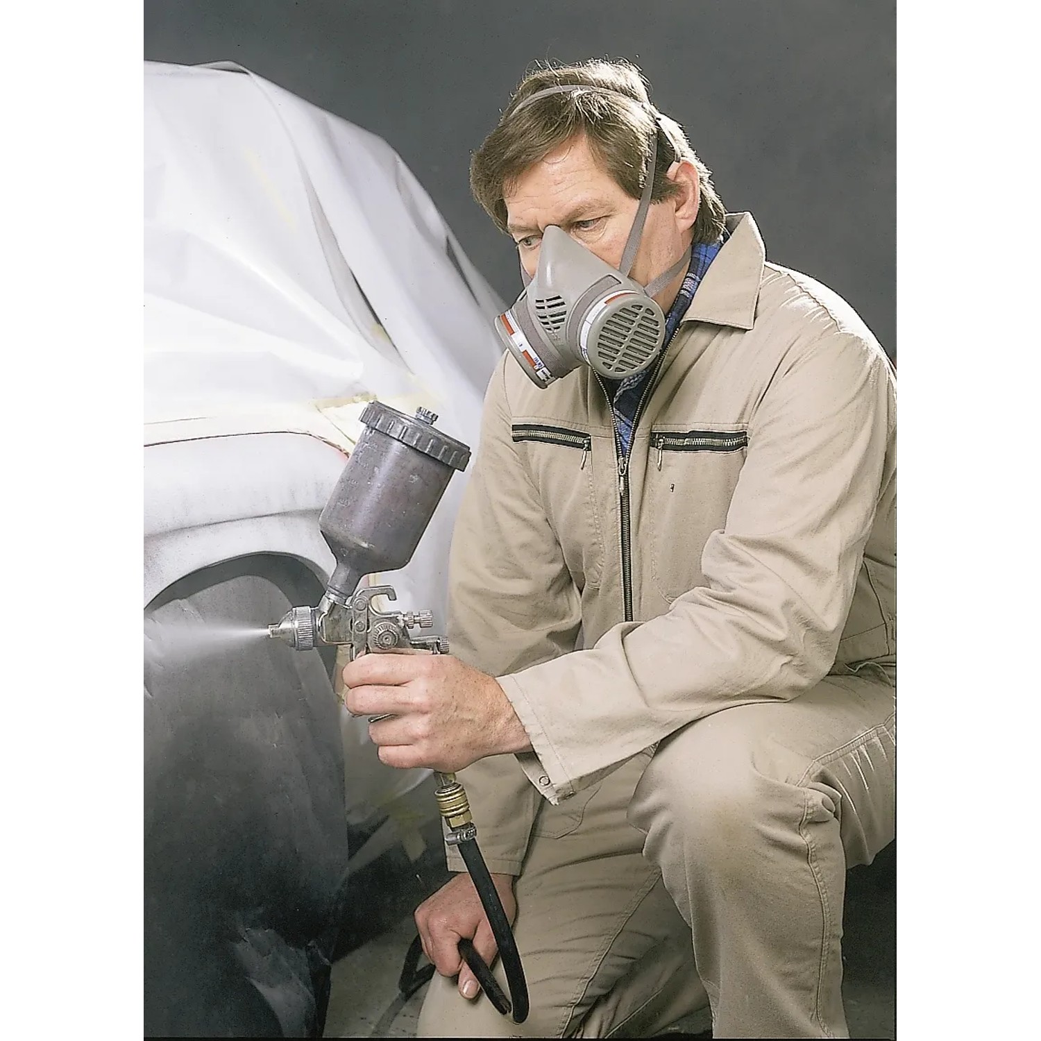 Uomo con respiratore e pistola a spruzzo. Cartuccia filtro LUX A1B1E1K1 per protezione respiratoria.