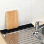 Tappetino scolapiatti Wenko Slim nero (42 cm) accanto al lavello con tagliere in legno per asciugare.