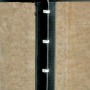 Applicazione di graffette a chiodo bianche (7-11mm) per il fissaggio di cavi su una struttura in legno scuro.