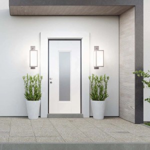 Porta blindata t.b.t. bianca con inserto in vetro, affiancata da luci esterne e piante.