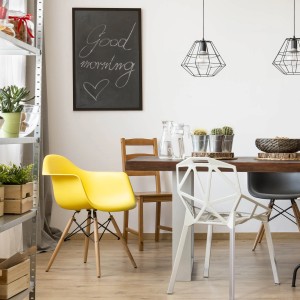 Soggiorno con lavagna, sedie e tavolo. Elementi decorativi come piante e lampade.