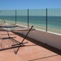 Recinzione in filo metallico come frangivista di fronte al mare blu, con amaca sulla terrazza. Arelle, ombreggianti e frangivista