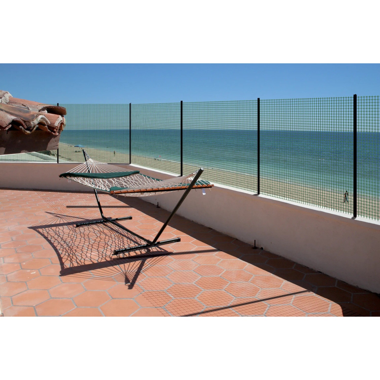 Recinzione in filo metallico come frangivista di fronte al mare blu, con amaca sulla terrazza. Arelle, ombreggianti e frangivista