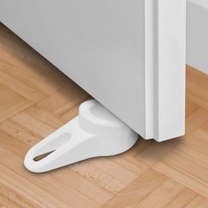 Fermaporta bianco t.b.t. in plastica sotto una porta su parquet.
