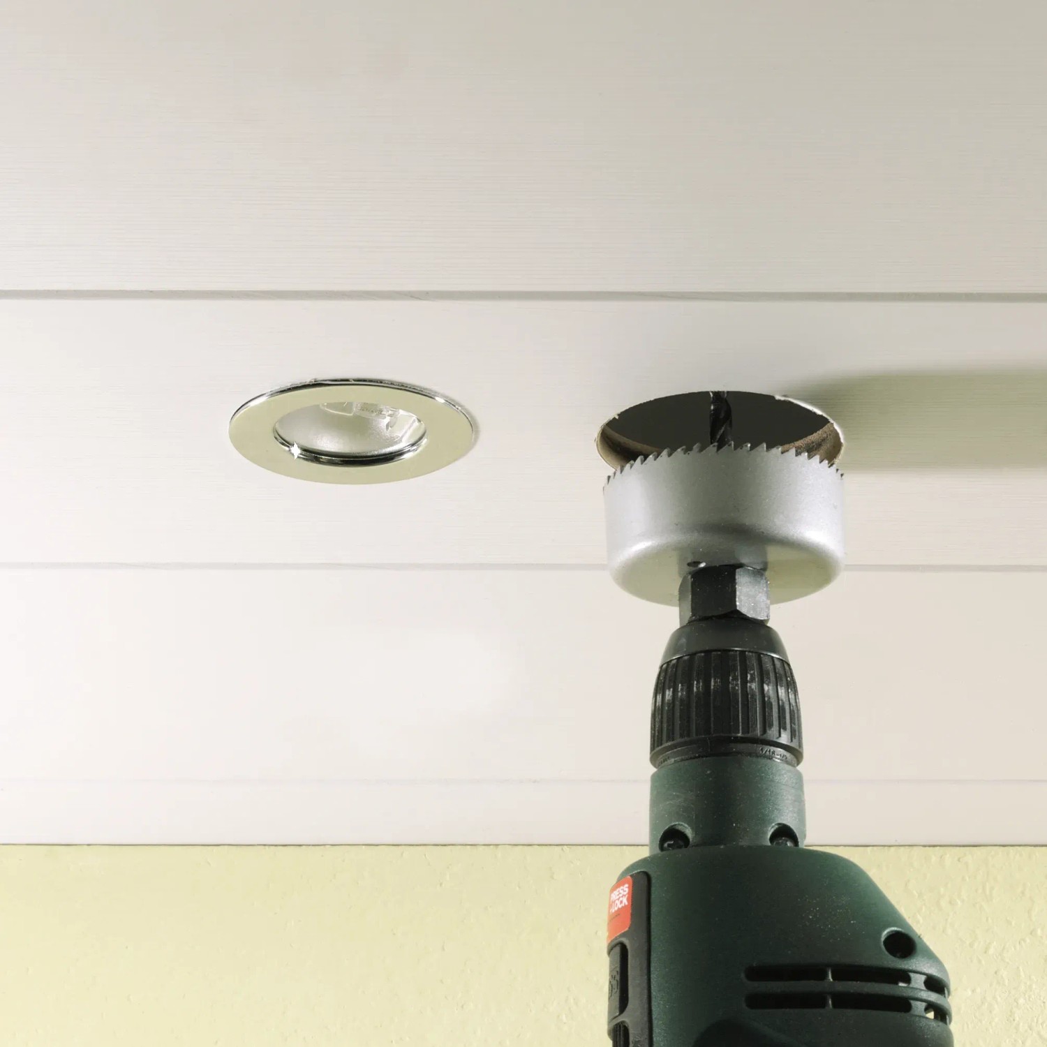 Set di seghe a tazza LUX in uso: sega a tazza su trapano che fa un foro per faretto a soffitto.