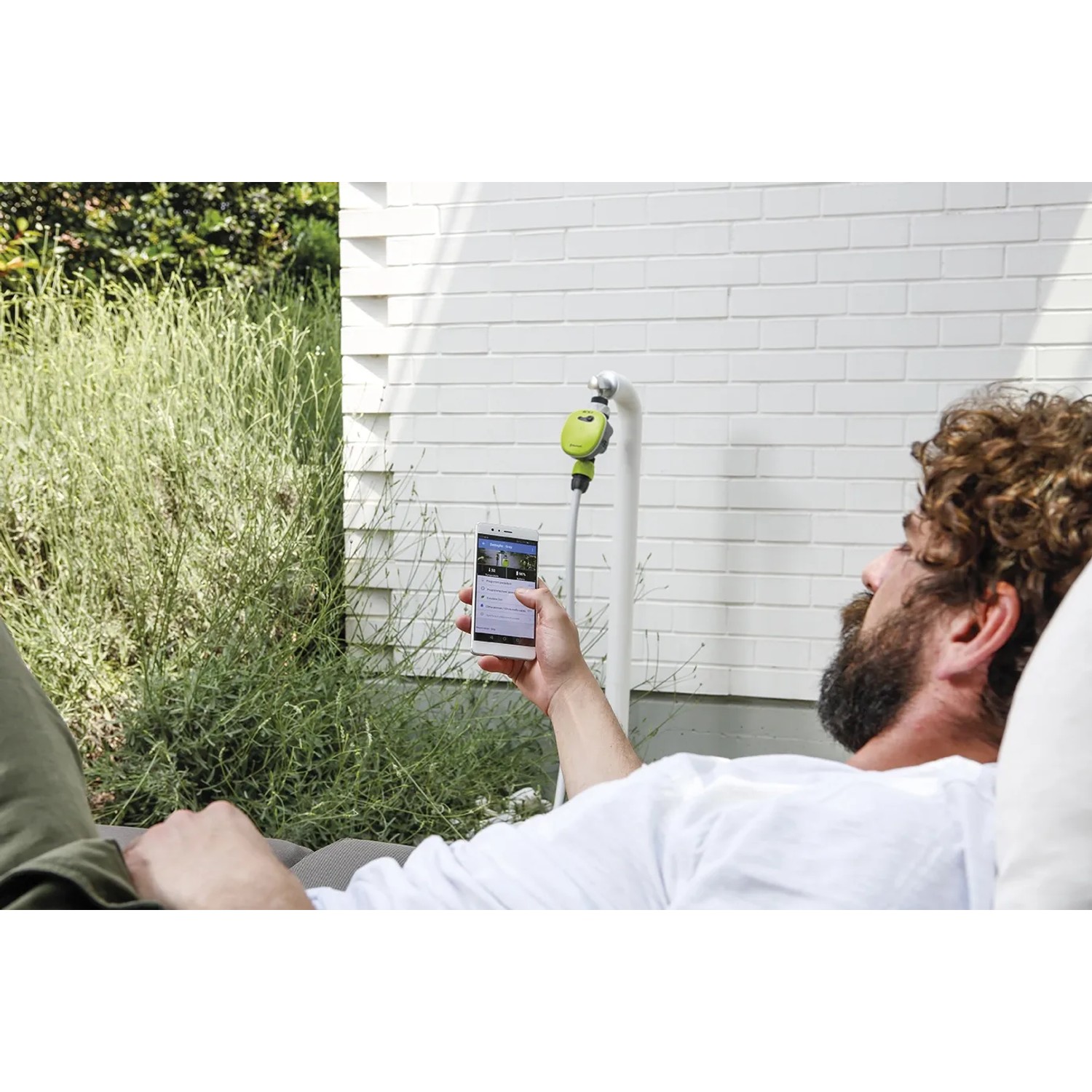 Uomo controlla l'irrigazione con l'app. t.b.t. dalla categoria Programmatori.