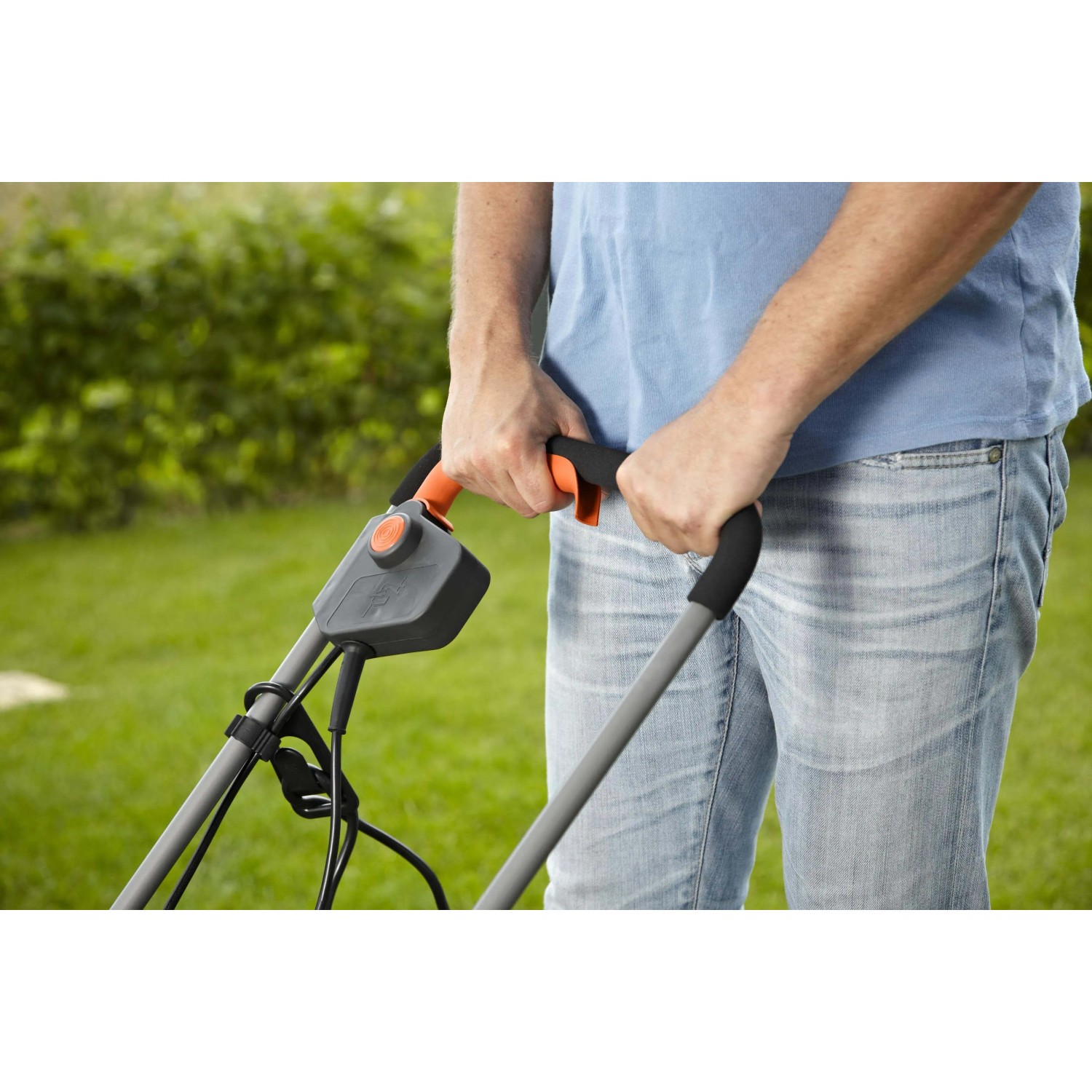 Primo piano: persona utilizza un tagliaerba elettrico t.b.t. con manico grigio e dettagli arancioni.