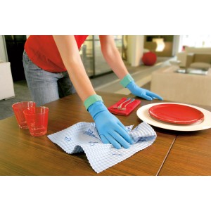 Mani che indossano guanti Vileda Comfort & Care S per pulizie domestiche mentre puliscono un tavolo.
