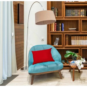 Poltrona turchese con cuscino rosso davanti a libreria e lampada da terra.