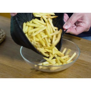 Patatine fritte versate da un contenitore nero t.b.t. in una ciotola di vetro.