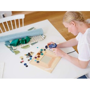 Donna che usa la pistola per colla a caldo per creare una cornice con bottoni.