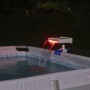 Cascata per piscina Flowclear™ con luce LED sul bordo piscina, illuminata di rosso.
