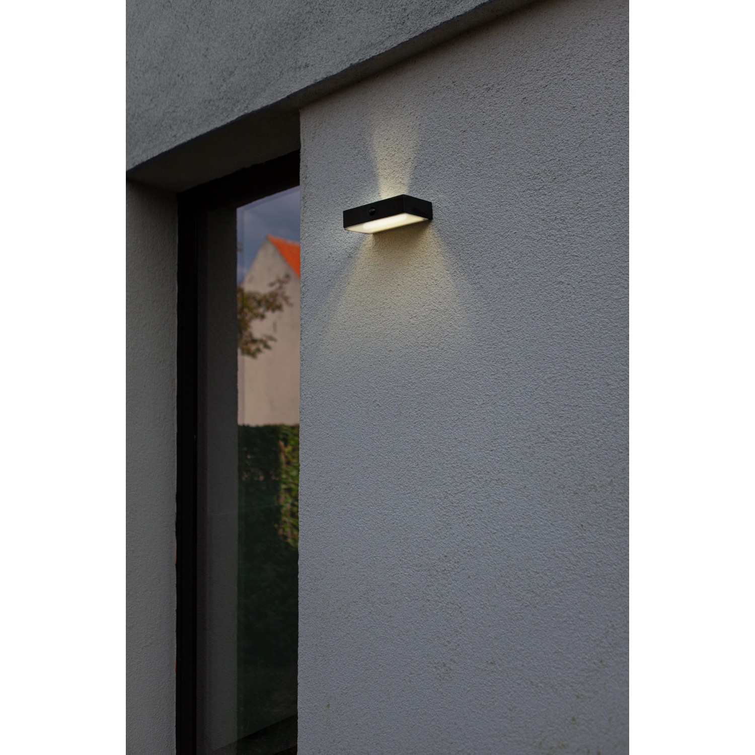Lampada da parete solare a LED Lutec Fadi nera, rettangolare con sensore di movimento su muro di casa.