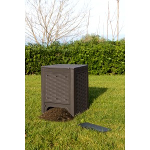Compostiera t.b.t. marrone in giardino con terra di compostaggio davanti.