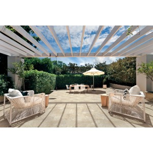 Terrazza con piastrelle per pavimenti t.b.t. sotto una pergola, mobili da giardino sullo sfondo.