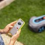 Smartphone che controlla un robot tagliaerba in giardino.