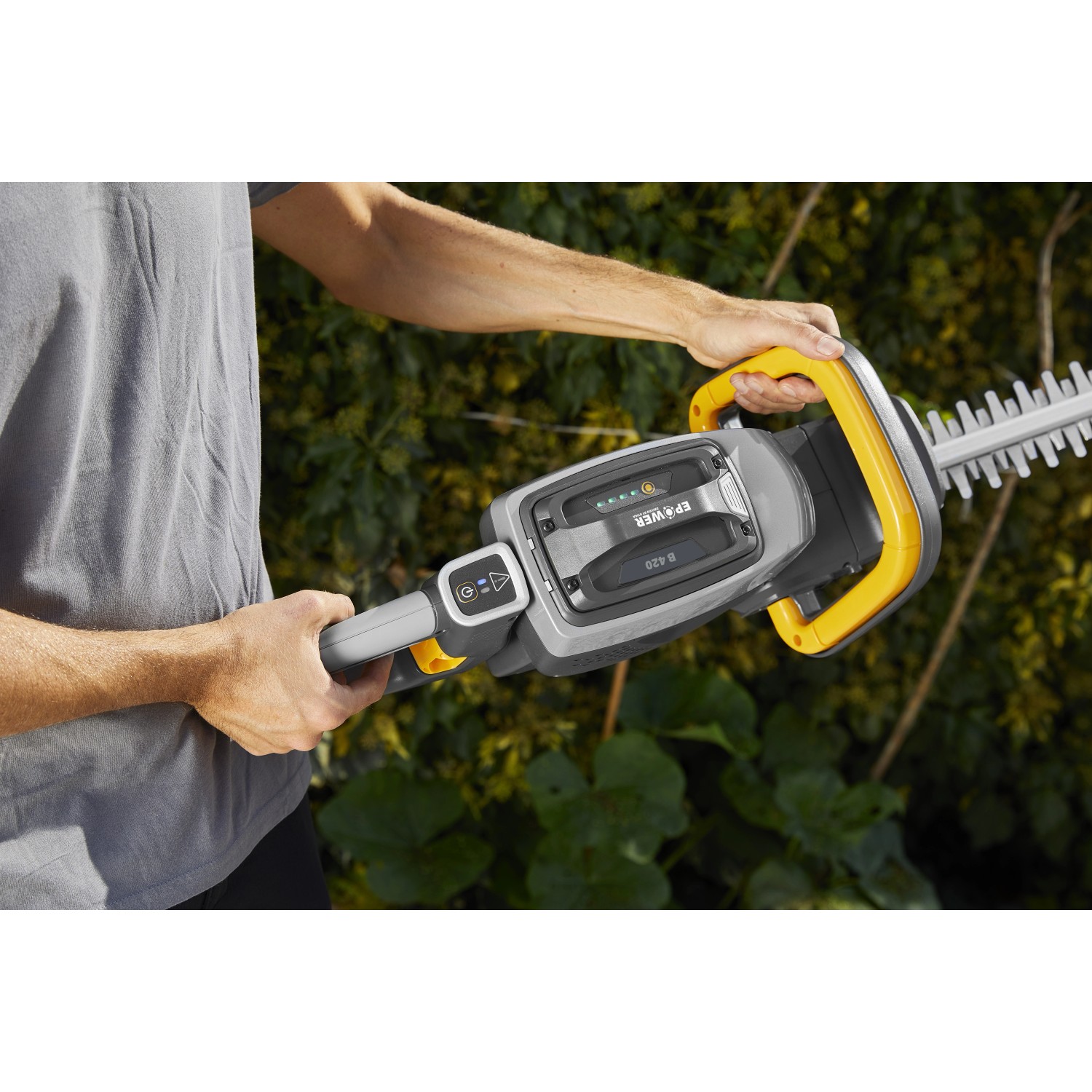 Tagliasiepi a batteria t.b.t. in azione, corpo grigio con dettagli gialli.