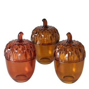 Tre barattoli decorativi in vetro marrone a forma di ghianda, ideali come regalo.