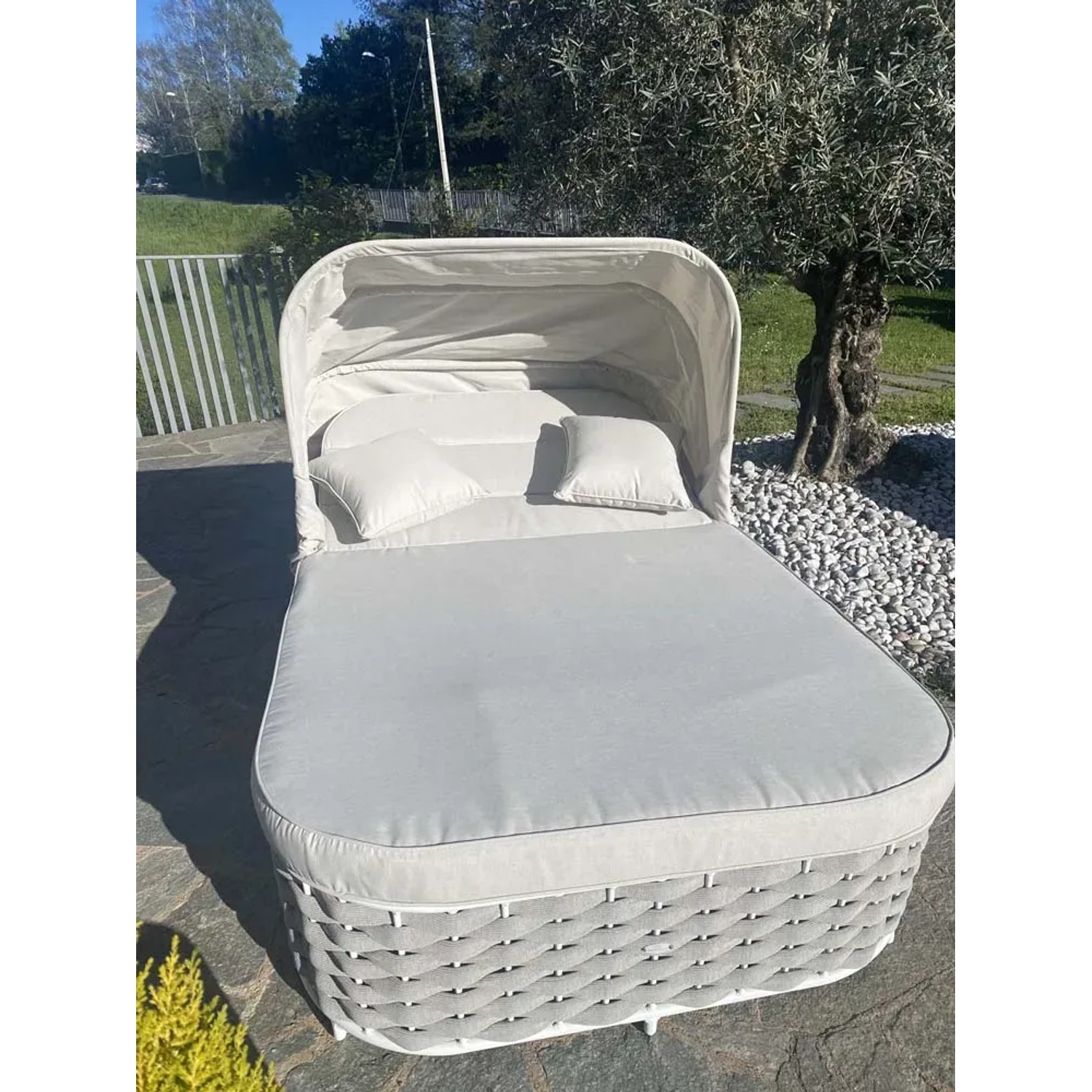 Lettino prendisole t.b.t. grigio con baldacchino e cuscini in giardino.