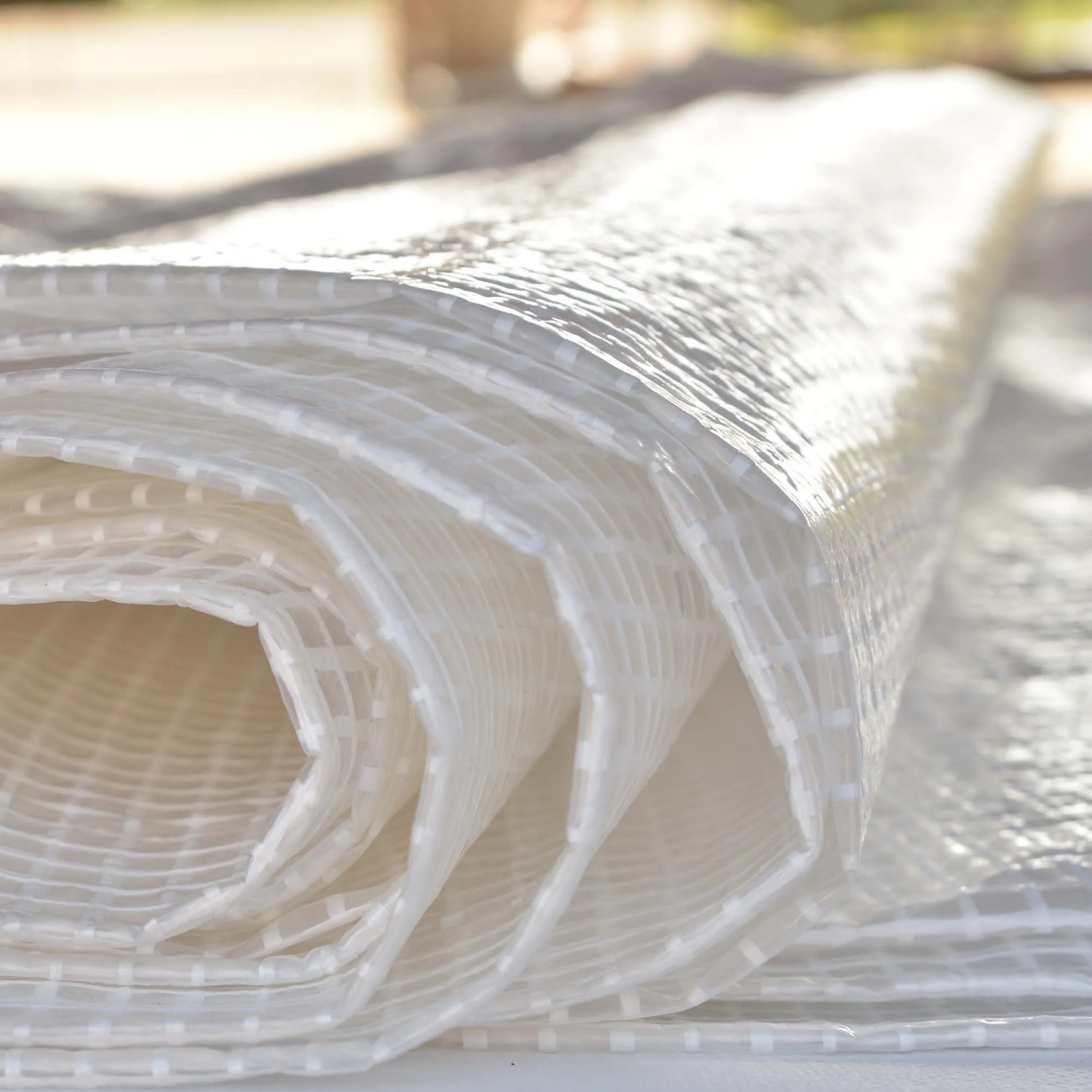 Telo di copertura trasparente arrotolato con motivo a griglia, adatto per il giardino.