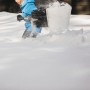 Persona che spalare la neve con la pala da neve telescopica Fiskars X-series.