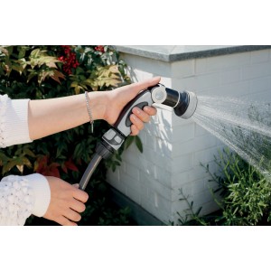 Mano che tiene la pistola per irrigazione t.b.t., getto d'acqua visibile.