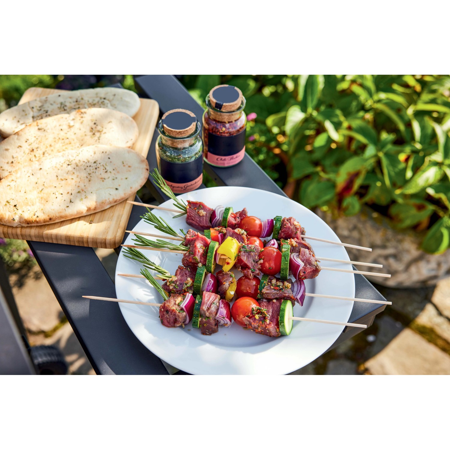 Spiedini alla griglia con verdure e pane su un tavolo, scena barbecue.