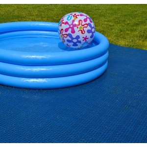 Piscina blu con palla su piastrelle scure per esterni.