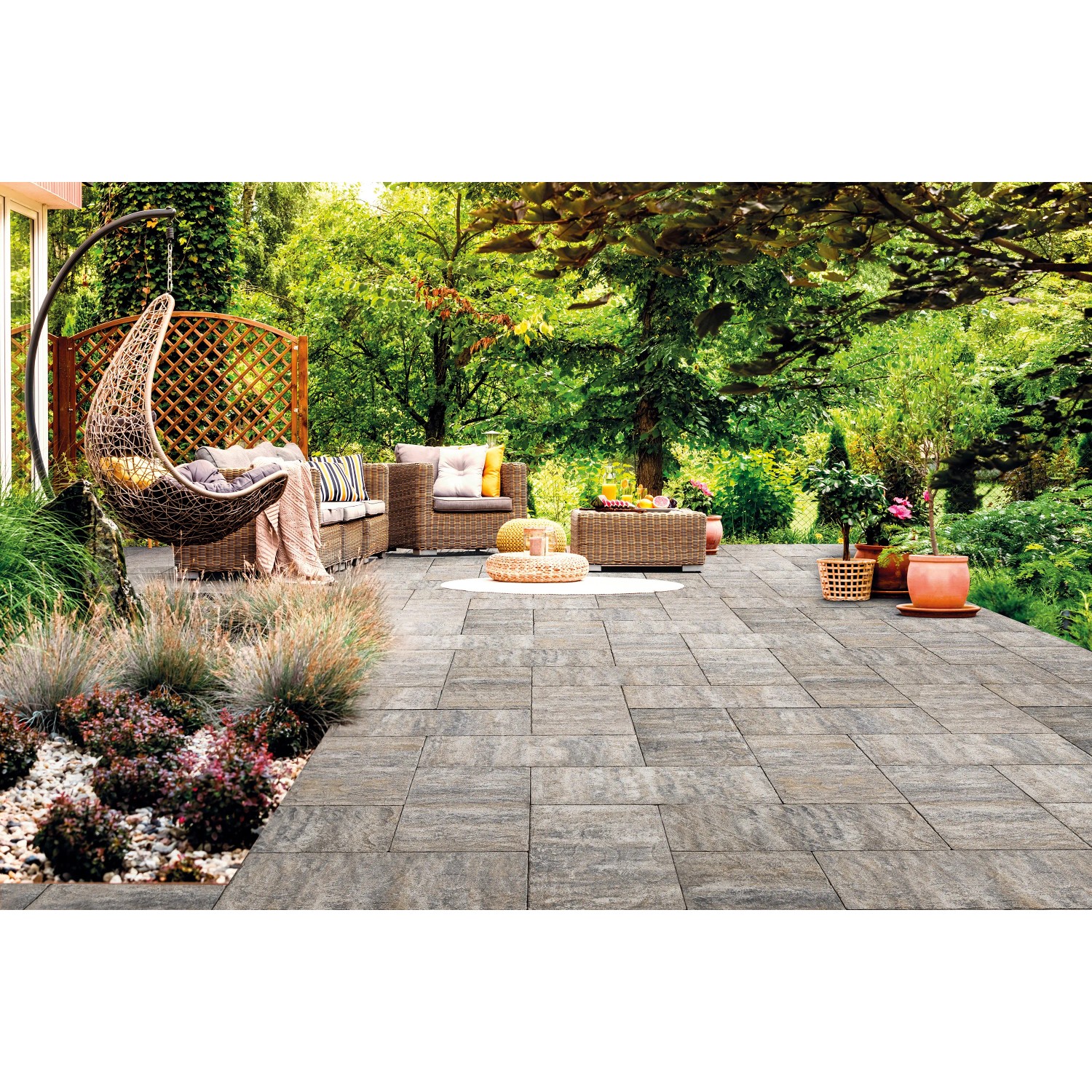 Terrazza con pavimentazione per esterno t.b.t. e mobili da giardino nel verde.
