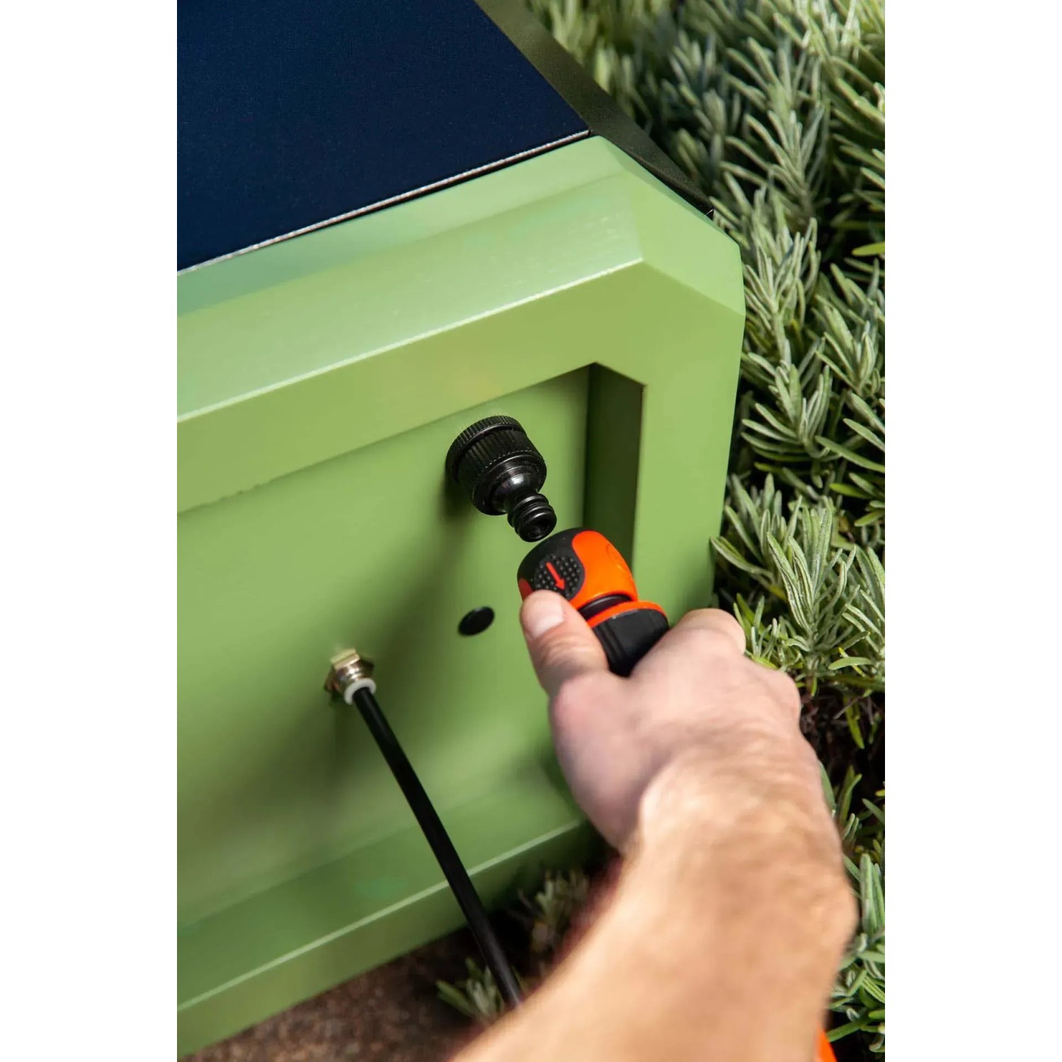 Pompa a pressione collegata all'armadietto da giardino verde.