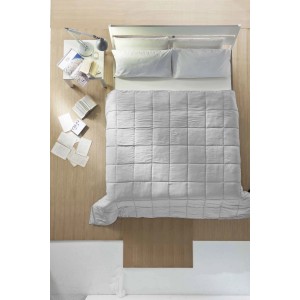 Letto con piumone trapuntato t.b.t. grigio e cuscini, fotografato dall'alto.