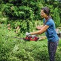 Donna taglia siepe con tagliasiepi a batteria Einhell Power X-Change GC-CH 18/40 Li Solo in giardino.