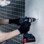 Un uomo fora un muro con una punta per piastrelle Bosch Expert.