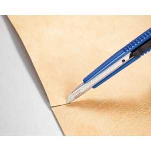 Cutter LUX (9 mm) con corpo in plastica blu taglia materiale beige.