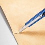 Cutter LUX (9 mm) con corpo in plastica blu taglia materiale beige.