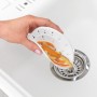 Filtro di scarico Wenko in silicone bianco con scarti alimentari sopra uno scarico del lavandino.