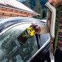 Uomo che utilizza il raschietto elettrico per ghiaccio Kärcher EDI 4 su un finestrino auto ghiacciato.
