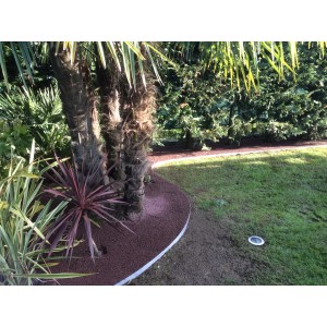 Giardino con Ciottoli e Granulati decorativi rossastri attorno a palme e come bordura del sentiero.