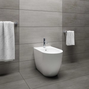 Bidet bianco moderno in bagno con piastrelle grigie.