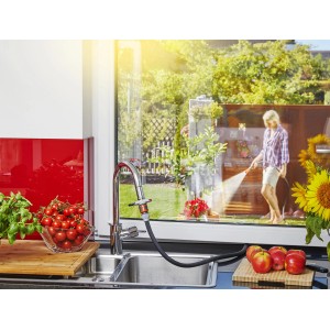 Connettore Gardena per rubinetti interni in uso, donna che annaffia il giardino.