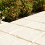 Piastrelle chiare t.b.t. per pavimentazione esterna, posate come vialetto da giardino.